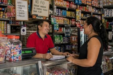 Tendero atendiendo a una clienta habitual en una tienda de barrio de Cali.